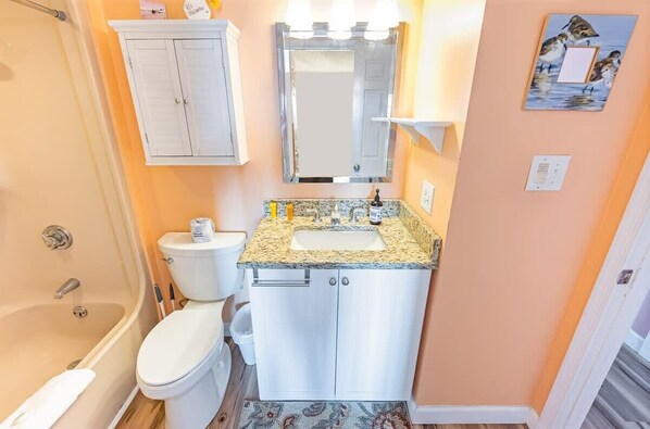 Een badkamer met een bad, toilet, wastafel en een spiegel boven de wastafel.