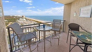 A balcony with a view of the beach, furnished with chairs and a table. - 1BR Oceanview Condo, Ocean Forest Plaza,High Floor (Myrtle Beach)