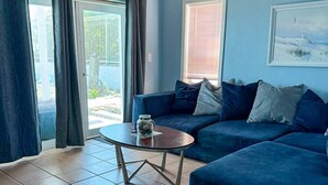 Una sala de estar con un sofá azul, una mesa de centro y un cuadro en la pared.