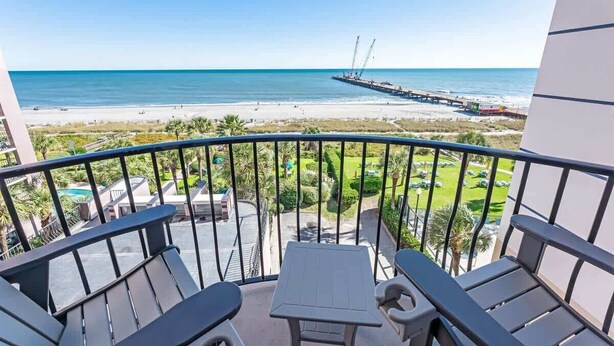En balkon med udsigt til stranden og molen.