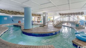 Une piscine intérieure avec un bord carrelé, un poste de surveillance pour les sauveteurs et un panneau indiquant qu’il est interdit de sauter.