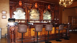 Eine Bar mit Holztresen, Barhocker und einer Kristallleuchtre.