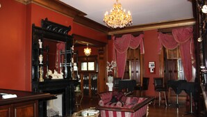 Ein traditionell eingerichteter Raum mit Kamin, einer Couch, einer Chandelier und einem Spiegel.