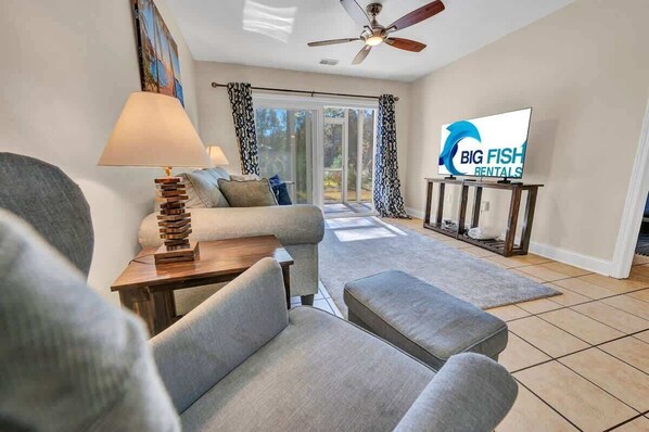 A modern living room with a sofa, a coffee table, and a TV displaying 'Big Fish Rentals' logo. - NEW Large 2BR- Pools - River Oaks Golf - Hot Tubs (Myrtle Beach)