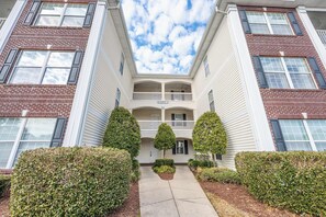 A two-story building with a central balcony, brick facade, and symmetrical windows. - NEW Large 2BR- Pools - River Oaks Golf - Hot Tubs (Myrtle Beach)