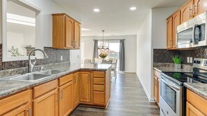 A modern kitchen with wooden cabinets, granite countertops, stainless steel appliances, and a view to the dining area. - Private Yard + Pond Views: Fort Wayne Family Home! (Fort Wayne)