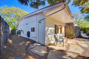 Una casa con patio, una zona de estar al aire libre cubierta y una cerca de madera.