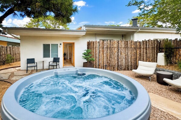 A hot tub in a backyard with a wooden fence, a chair, and a small table. - Serene Couple's Retreat 3 Mi to Dtwn Santa Fe (Santa Fe)