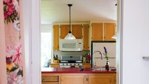 A kitchen with wooden cabinets, a microwave, a stove, and a refrigerator. - The Waldoboro Inn Room 1 (Waldoboro)