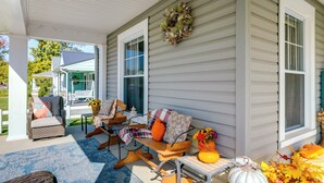 A porch with outdoor seating, a table with a pumpkin, and a wreath on the wall.