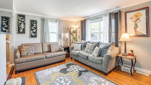 A living room with two sofas, a patterned rug, and a painting on the wall. - Global Staycation! Scenic Pikesville Family Home (Pikesville)