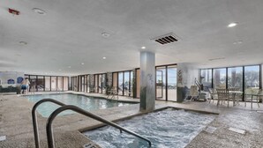 An indoor pool area with a hot tub, seating area, and large windows. - Studio Sand Castle South,Direct Ocean View, Pools! (Myrtle Beach)
