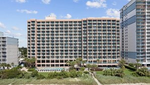 A large hotel with multiple floors, a swimming pool, and a beach area. - Studio Sand Castle South,Direct Ocean View, Pools! (Myrtle Beach)