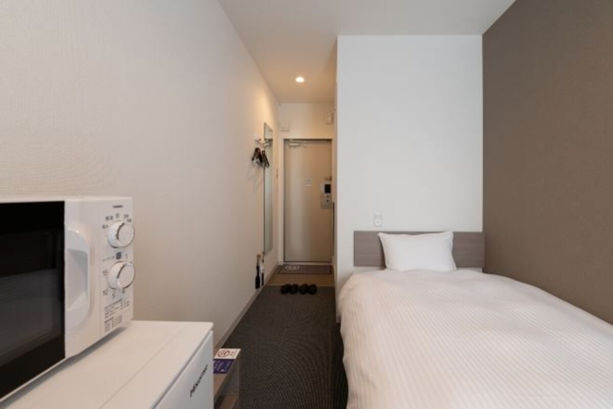 A hotel room with a bed, a TV, a microwave, and a small table.