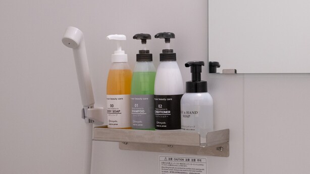 Un estante de baño con distintos artículos de aseo, como jabón corporal, champú, acondicionador y jabón de manos.