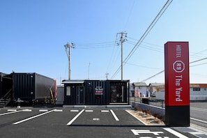 A hotel entrance with a sign indicating 'HOTEL 89 The Yard' and a parking lot with marked spaces. - Hotel R9 the Yard Kurashiki (Kurashiki)