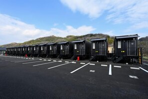 A row of train car-style cabins with a parking lot in front. - Hotel R9 the Yard Kurashiki (Kurashiki)