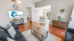 Ein geräumiges Wohnzimmer im modernen Stil mit einer großen Couch, einem Couchtisch und einem Essbereich mit einer Chandelier.