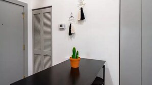 A room with a black table, a potted cactus, and a chair. There are two doors and a wall-mounted light fixture. - Near Hospitals & DT  ~  Vibey+Parking+W/D+Churchill (Louisville)