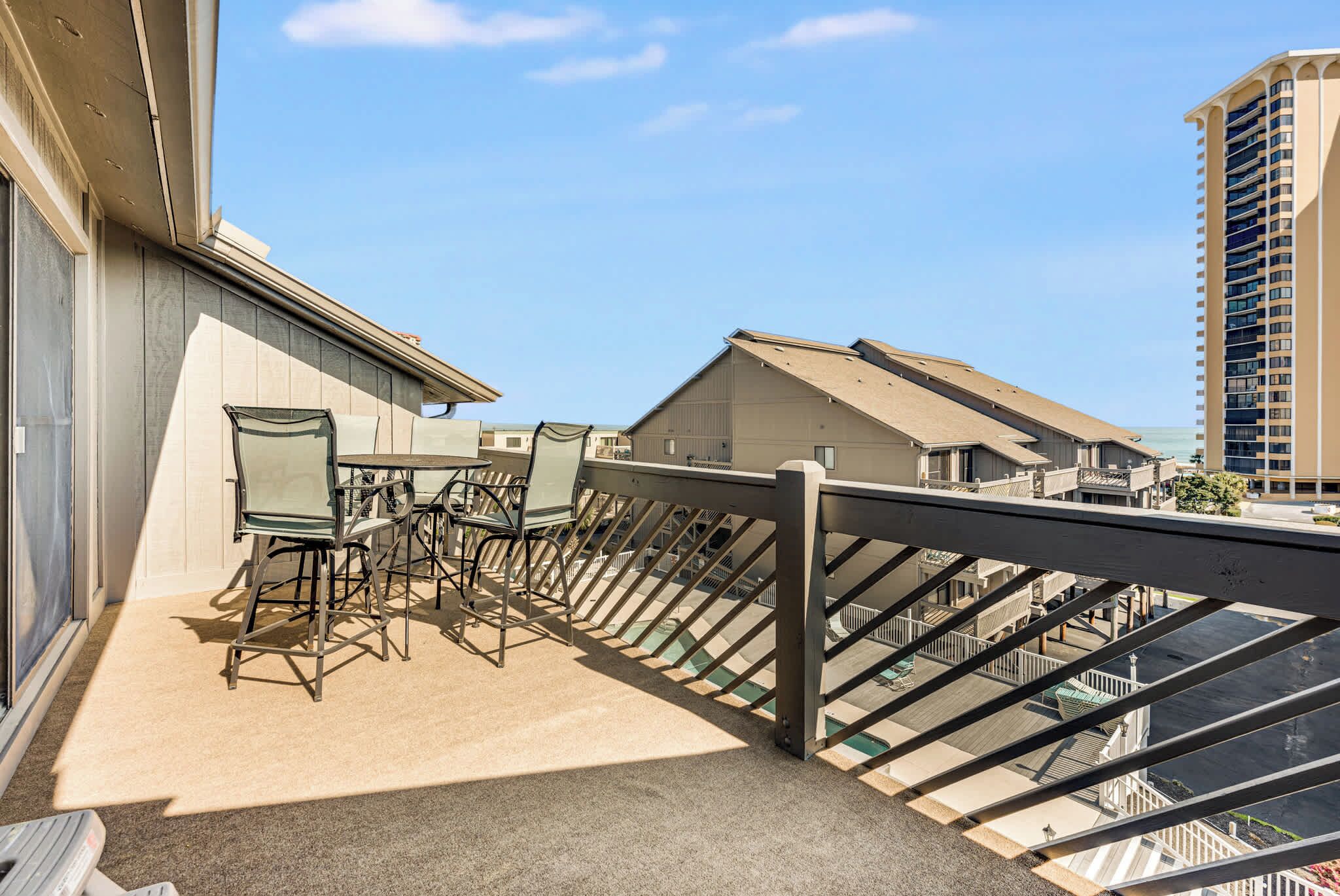 A balcony with a table and chairs, a railing, and a view of adjacent buildings.