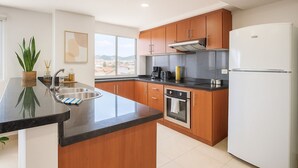 A modern kitchen with wooden cabinets, a stainless steel sink, and a white refrigerator. - Gran Esmeralda Space View and Style (Cuenca)