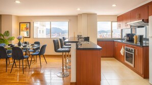 A modern kitchen with wooden cabinets, a stainless steel range hood, and a large window offering a city view. - Gran Esmeralda Space View and Style (Cuenca)