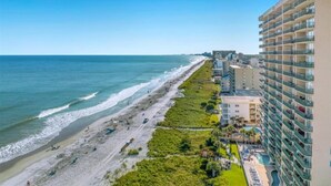 Ein Küstenhotel mit Blick auf den Strand, mehreren Stockwerken und einem Poolbereich.