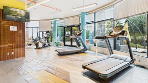 A modern gym with treadmills, stationary bikes, and a large window offering a view of the outdoors. - Your Private Downtown Oasis (Victoria South)