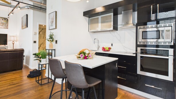 A modern kitchen with black and white cabinetry, stainless steel appliances, and a marble countertop. - Your Private Downtown Oasis (Victoria South)