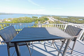 A balcony with a table and chairs overlooking a body of water and a cityscape. - Cozy beach condo on desirable Fort Myers Beach - Unit 1107 (Fort Myers Beach)