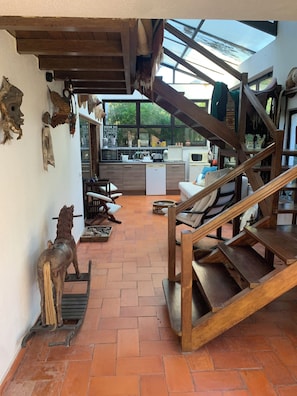 A rustic interior with a wooden staircase, a kitchen area, and a dining space.