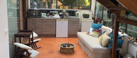 Amplia sala de estar con sofá, una mesa de centro y un comedor con barra de cocina.