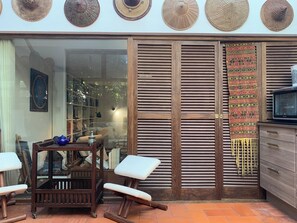 A room with a wooden sliding door, a television, a patterned rug, and a bookshelf with various items.