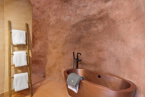 Badkamer | Een aparte badkuip en douche, een haardroger, handdoeken, zeep