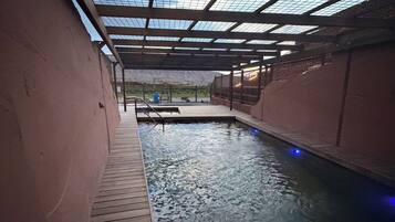 Una piscina interior con cubierta de madera y techo de cristal.