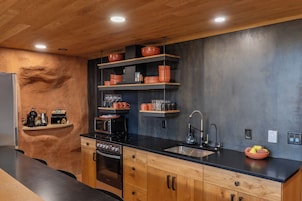 Una cocina moderna con armarios de madera, encimera negra y horno empotrado.