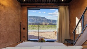A bedroom with a large bed, a view of a vineyard, and a staircase. - Honey Rock Landing (Delta)