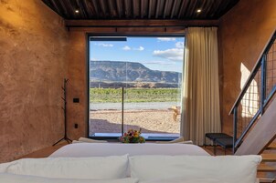 Un dormitorio con una cama grande, vistas a un viñedo y una escalera.