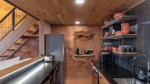 A modern kitchen with a wooden staircase, stainless steel countertops, and a built-in oven. - Honey Rock Landing (Delta)