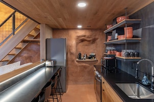 Una cocina moderna con escalera de madera, encimeras de acero inoxidable y horno empotrado.