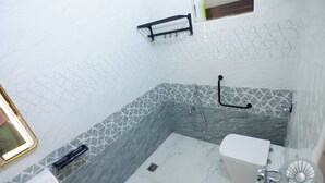 Un baño con inodoro blanco, lavamanos y zona de ducha.