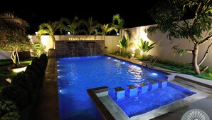 Una piscina con una pared de piedra y un cartel que dice "PEARL PARADISE".