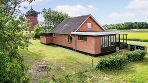 Une maison en briques avec un toit en pente, une véranda et un jardin clos.
