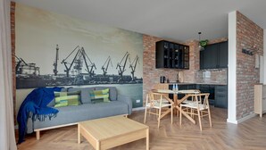 Un salon moderne avec un canapé, une table basse et une fresque représentant des grues sur le mur.