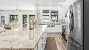 A modern kitchen with a large island, stainless steel appliances, and a view to the outdoors.