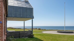 Ein modernes Gebäude mit einer überdachten Terrasse mit Blick auf die Küste.
