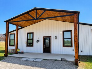 A single-story building with a covered porch, a front door, and two windows.