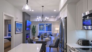 A modern kitchen with a central island, built-in appliances, and a dining area with a chandelier.