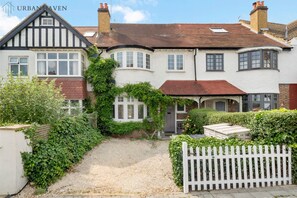 A traditional two-story house with a white facade, dark timber framing, and a red-tiled roof. - Spacious 4 bed House | Parking | Garden | 500gb WiFi (London)