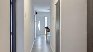 A narrow hallway with a door at the end, a small table with a chair, and a window with blinds. - Stunning home in Salopeki Modruski with WiFi (Salopeki Modruski)